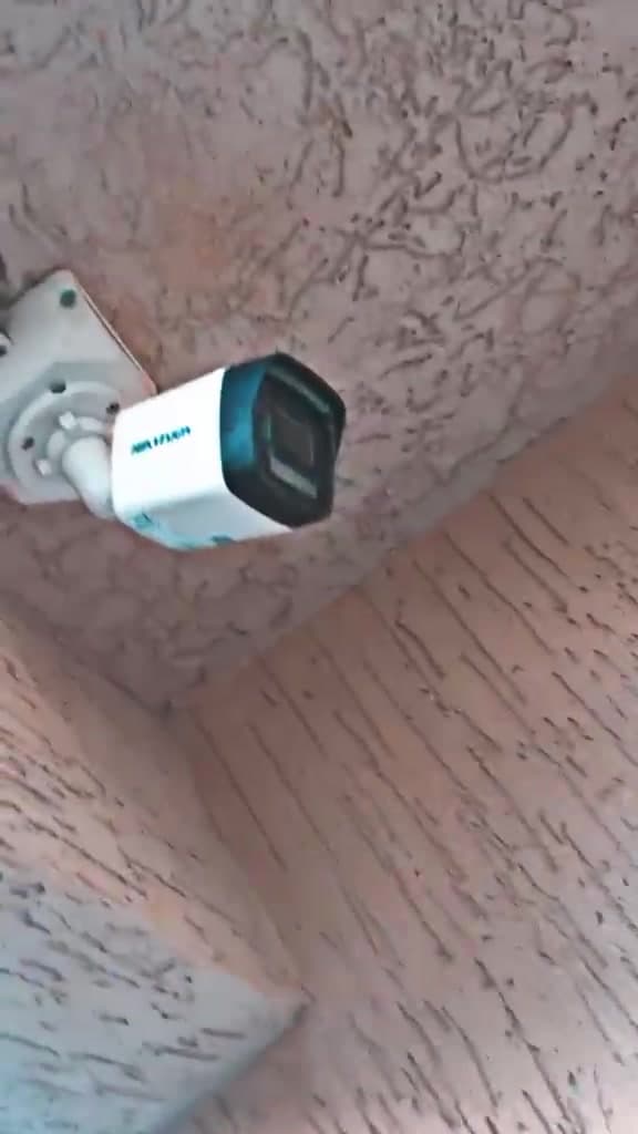 External bullet security cameras mounted on a rendered wall beneath the roof eave of a building