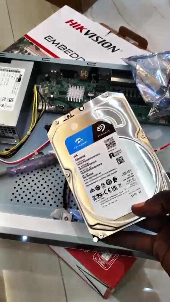 Surveillance hard drive being fitted into an opened network video recorder during a CCTV installation