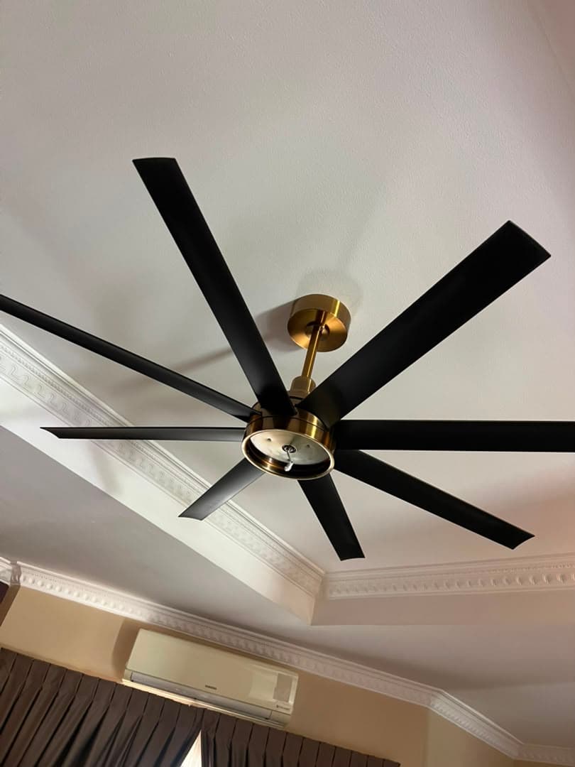 Large black and brass six-blade ceiling fan installed on a finished ceiling