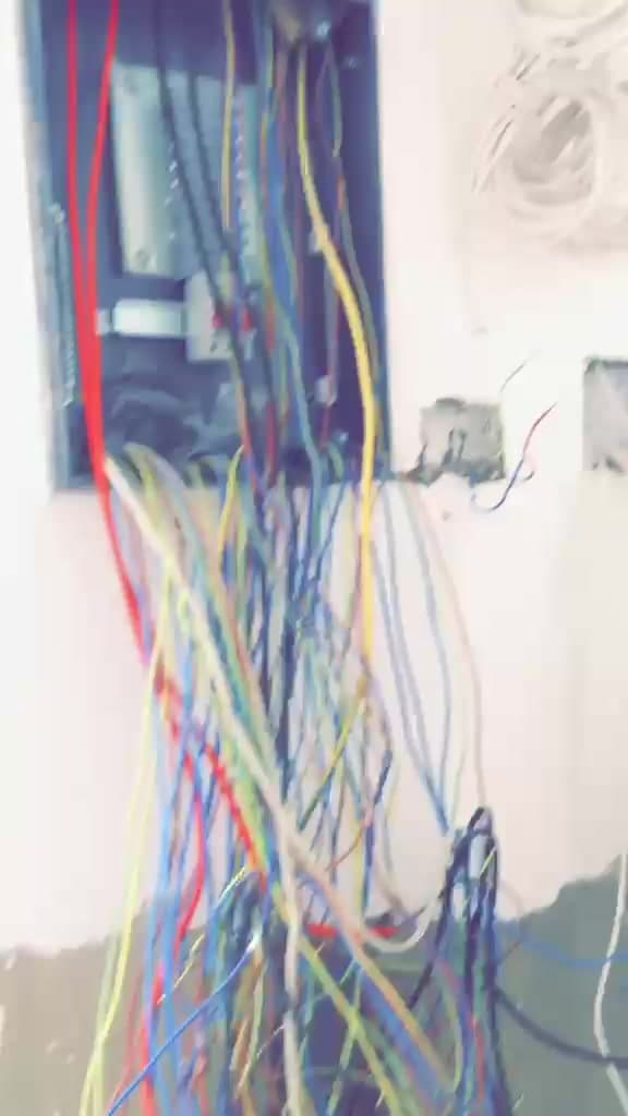 Distribution board enclosure with coloured circuit conductors drawn in, coiled cable runs parked on the wall and back boxes set for switches and sockets