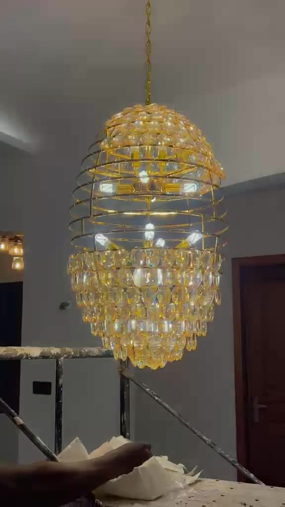 Large lit crystal chandelier hanging in a room during commissioning