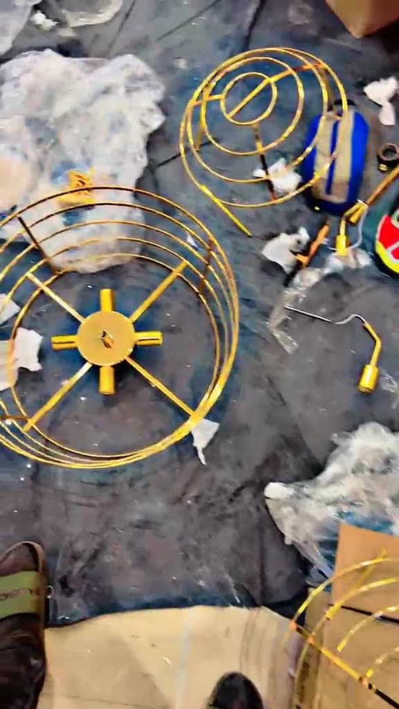 Brass chandelier rings and fixings laid out on a protected floor before assembly