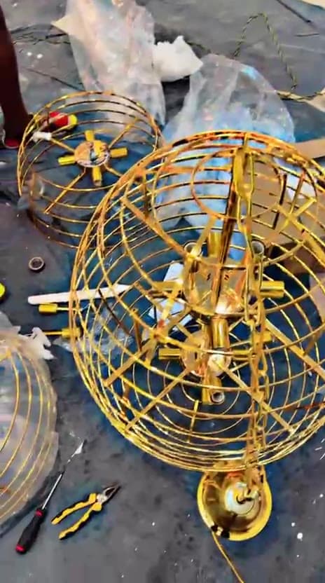 Brass chandelier frame being assembled from components on a protected floor