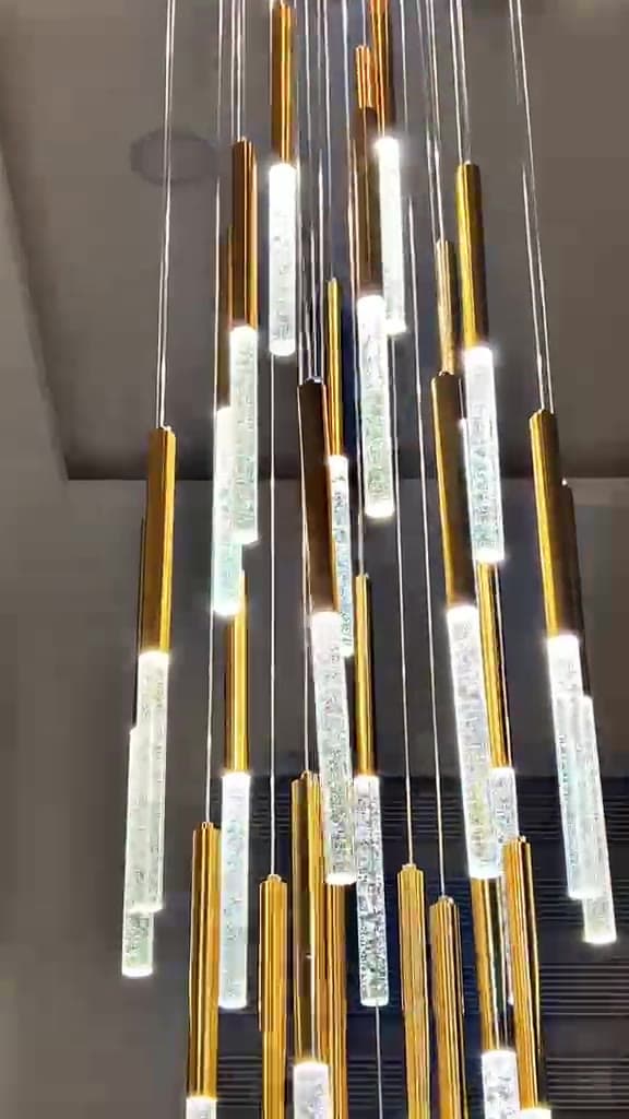 Cluster of illuminated brass and crystal rod pendant lights installed on a dark ceiling