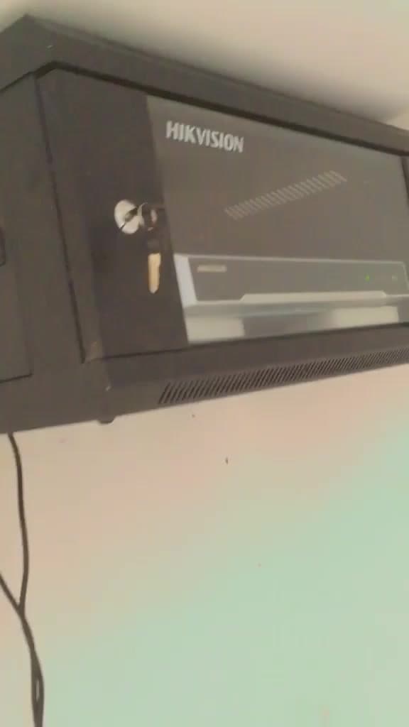 Lockable wall-mounted network cabinet housing a network video recorder, fixed at high level with the key in the door